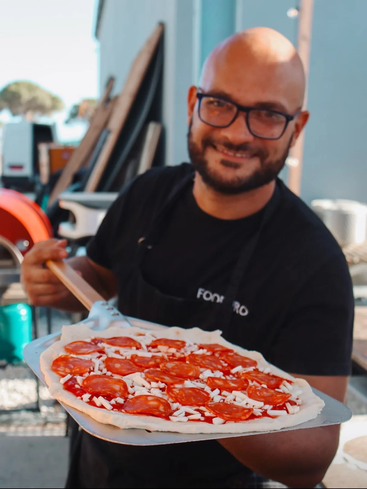 Chef Mario Ruggeri holding a pizza